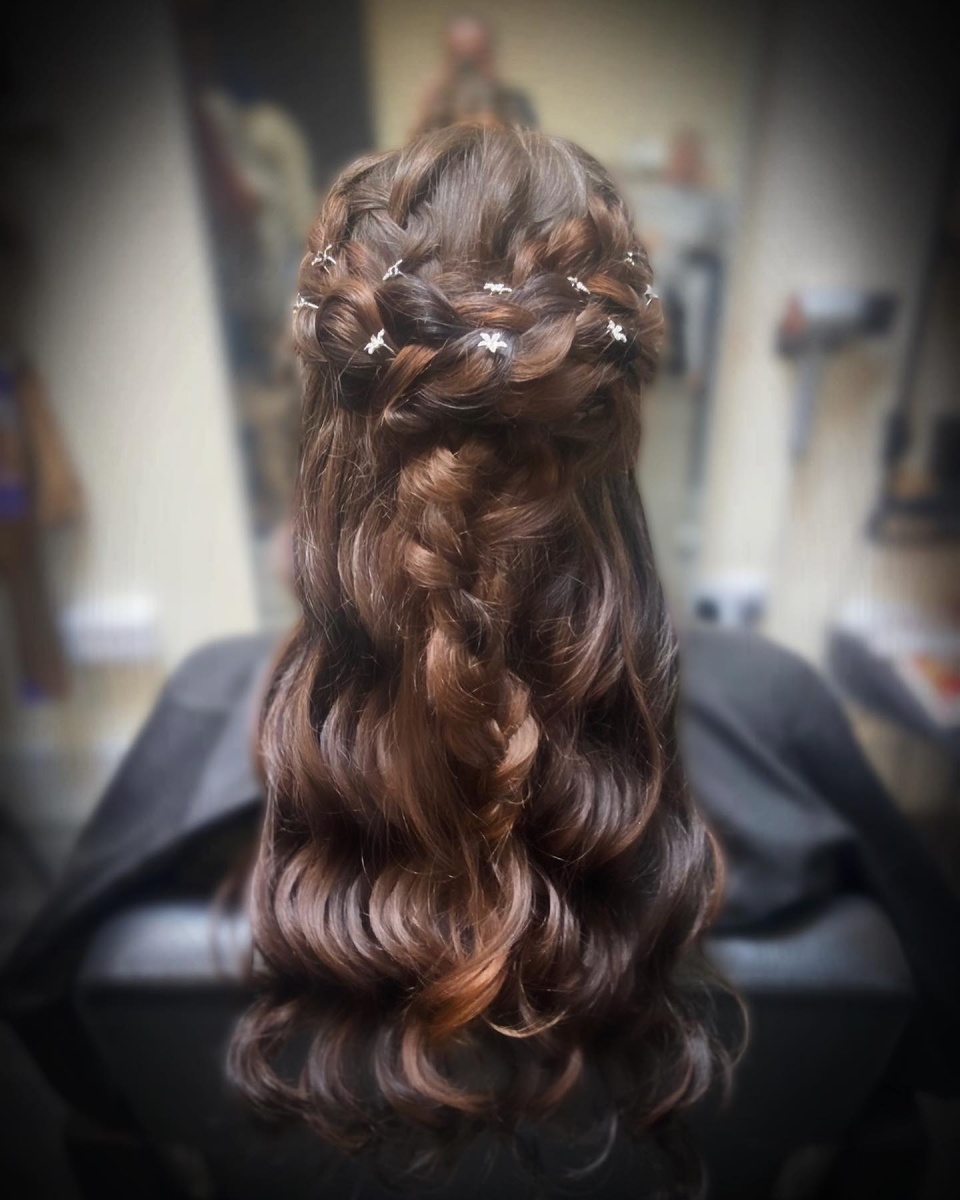 Image of someone’s brunette hair with plait in it and flower decoration.