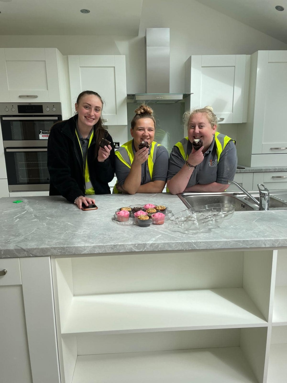 Group of women cleaners posing with cupcakes in a clean kitchen