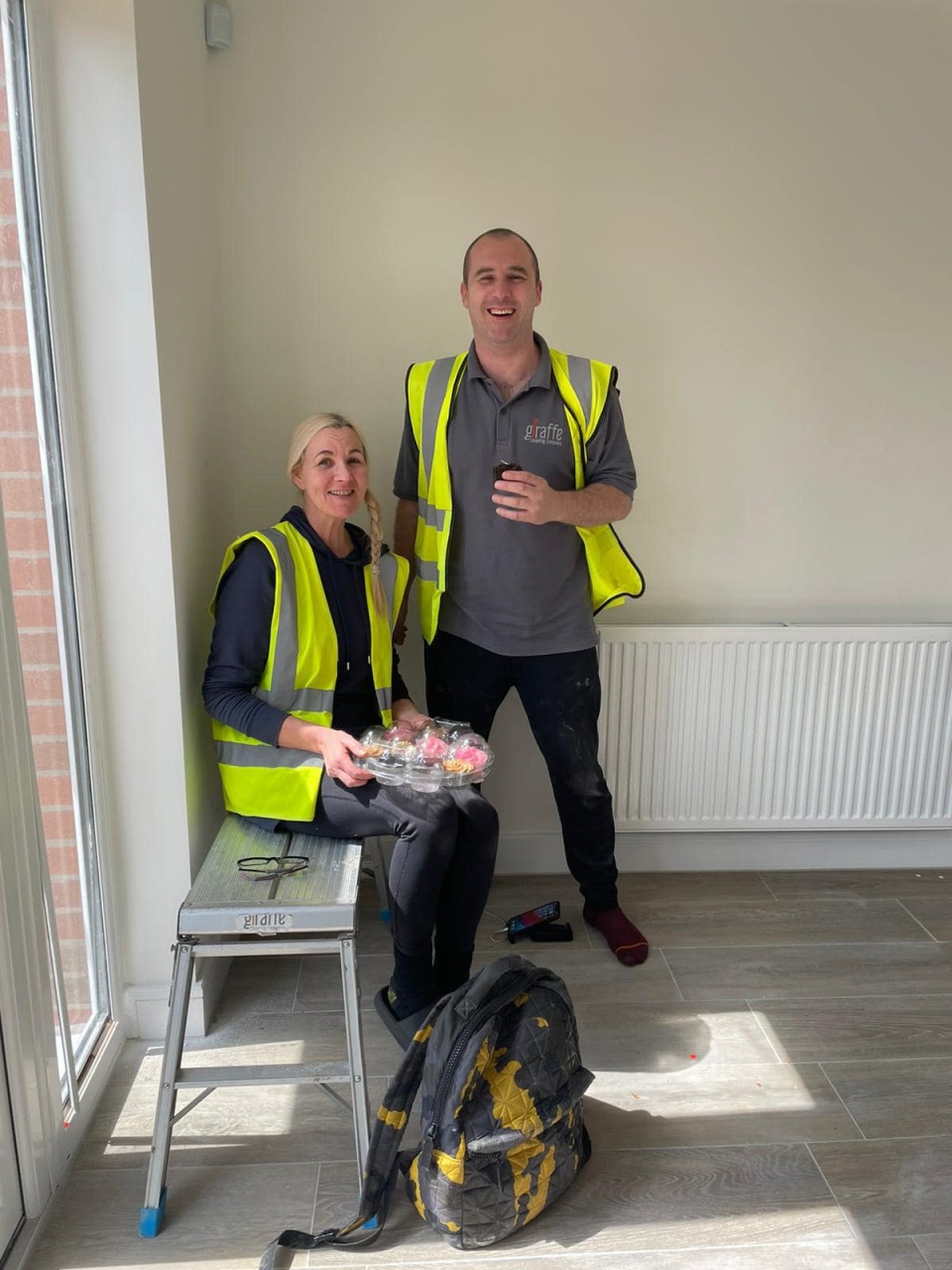 Two cleaners man and woman posing with cupcakes in a clean home