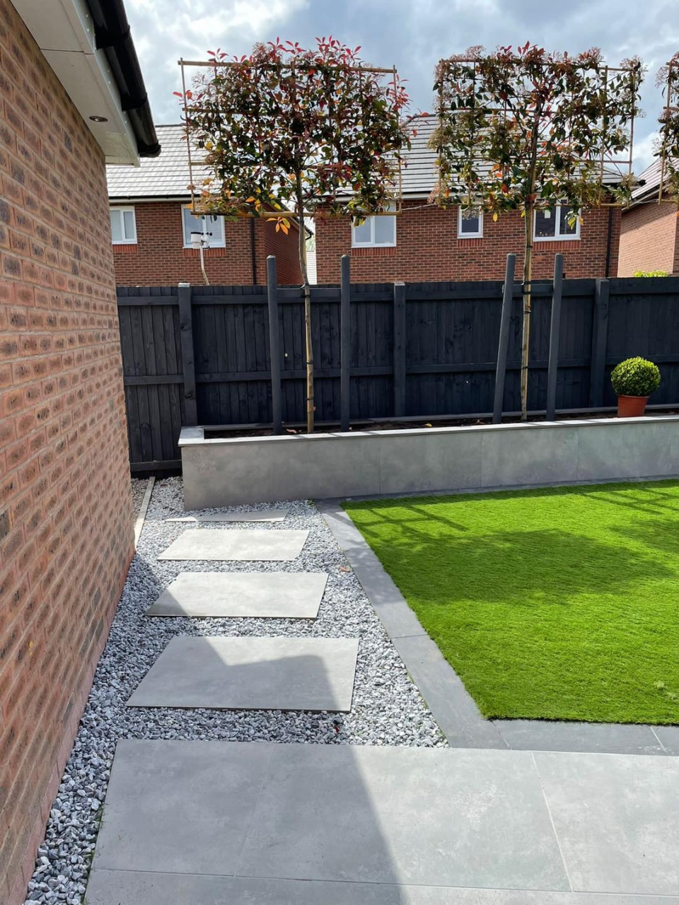 Image of pebbles and walk way in garden next to fake grass