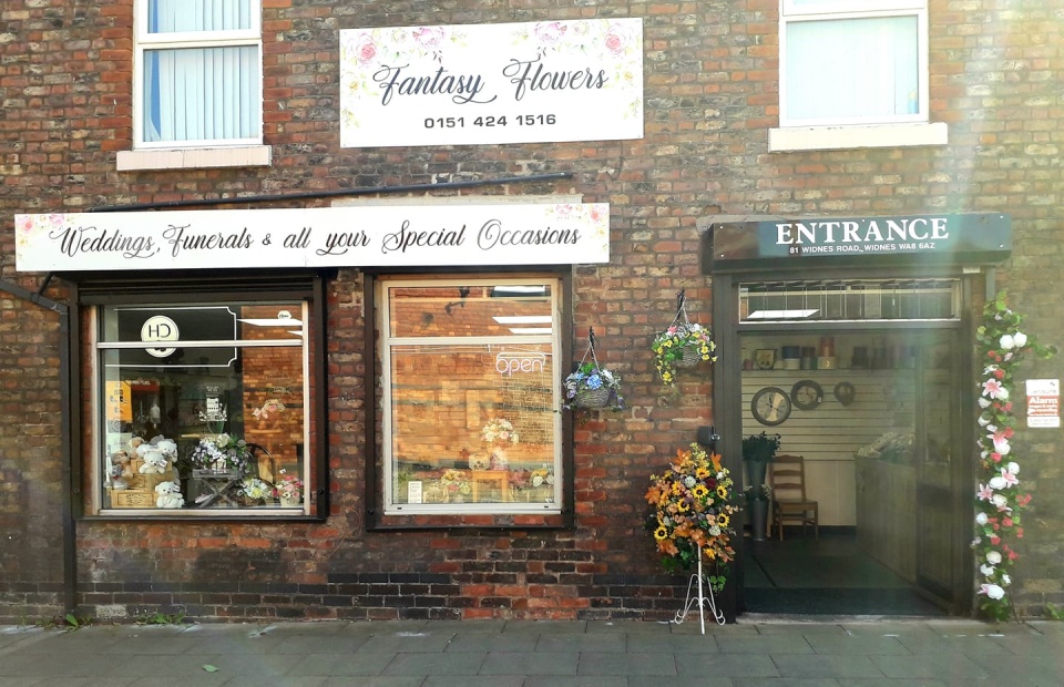 An image of Fantasy Flowers store front. The text is decorative with flowers, stating 'weddings, funerals & all your special occasions'