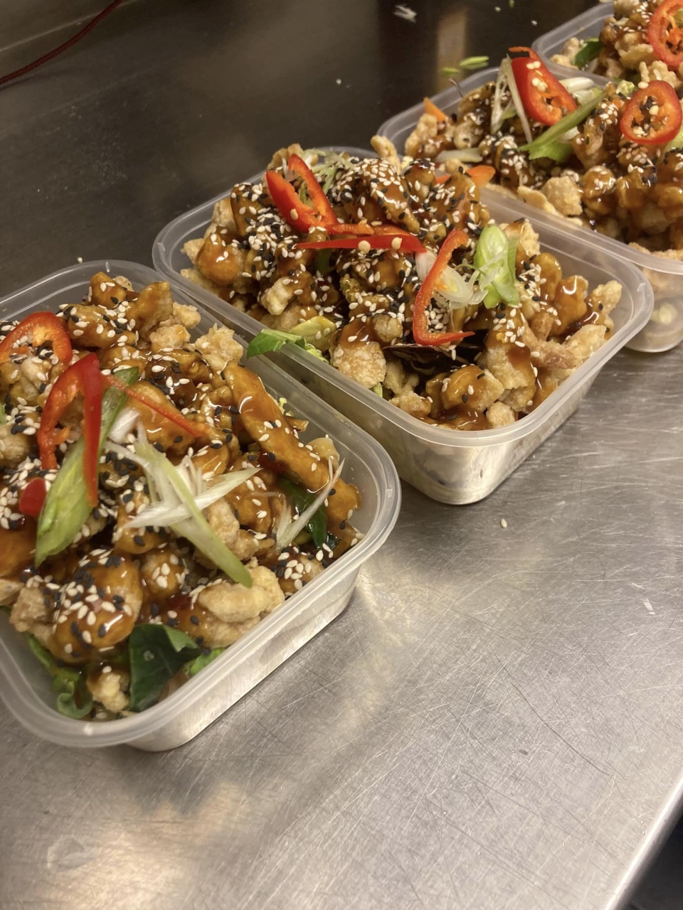 Fresh vegan noodle boxes with Asian style vegetables, mushrooms, covered in sauce and sesame seeds