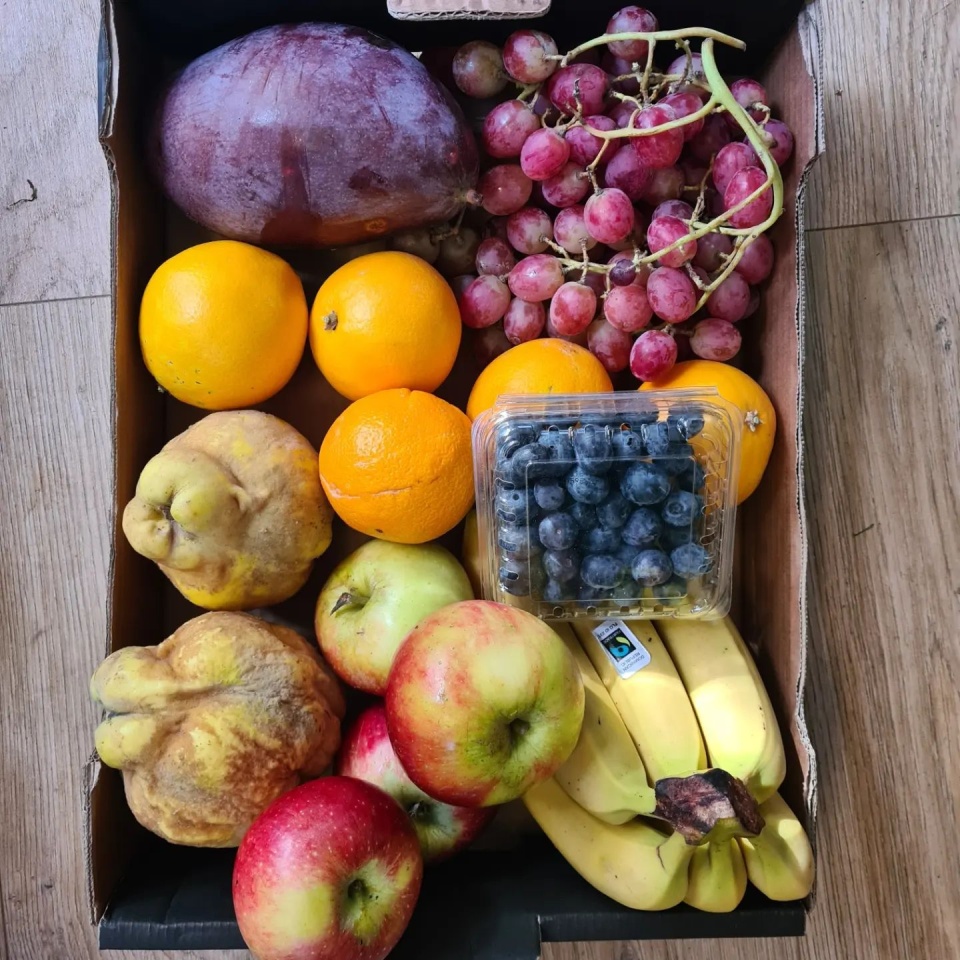 Fruit and veg box, brightly coloured, grapes, blueberries, apples, oranges, bananas and pears