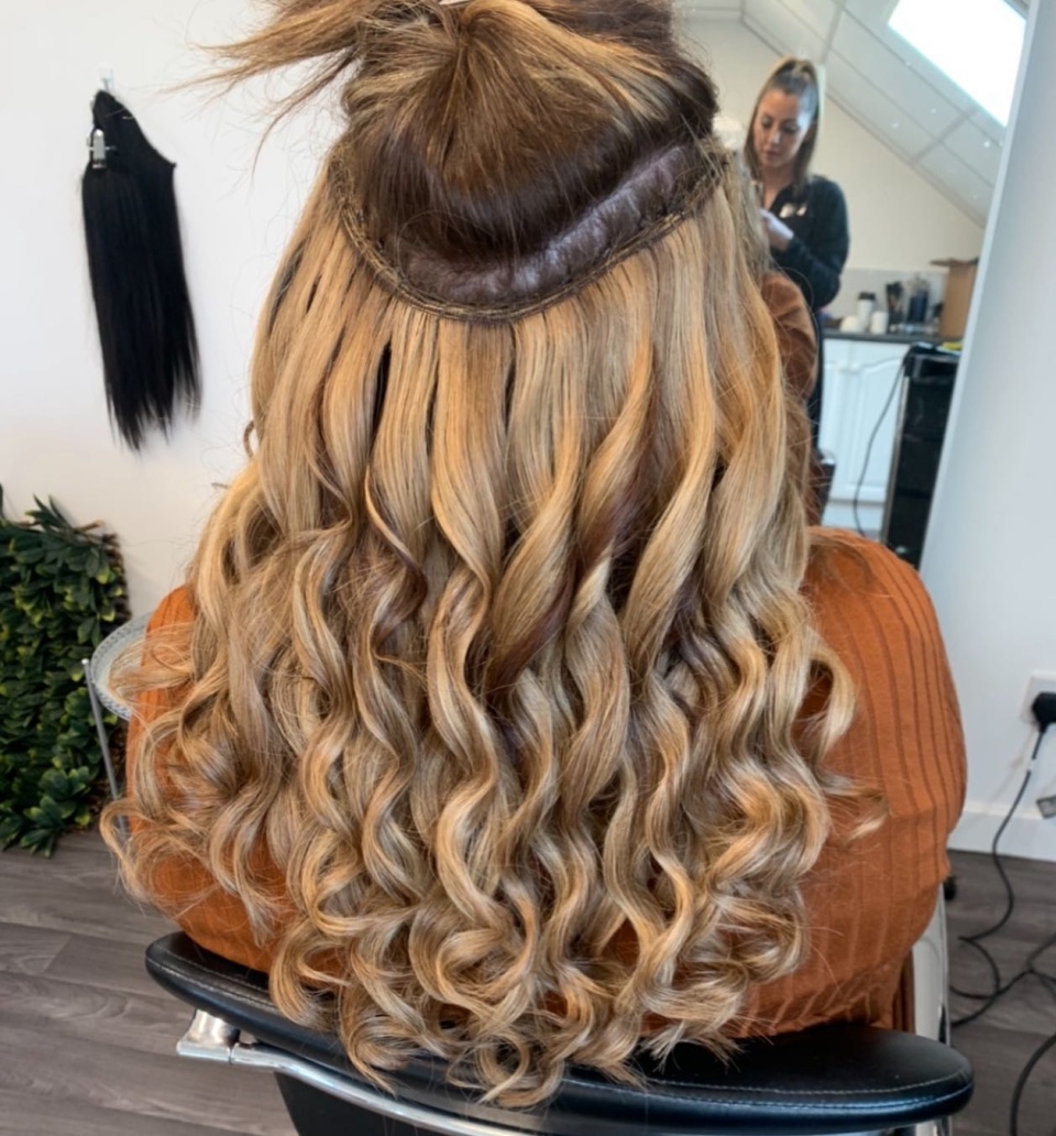 Image of the back of someone’s head, with blonde and Brown extensions inserted into the back