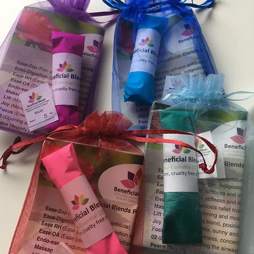 a few essential oil blends photographed next to each other in fabric bags, each is a different colour, pink, blue, red/peach and green/blue.